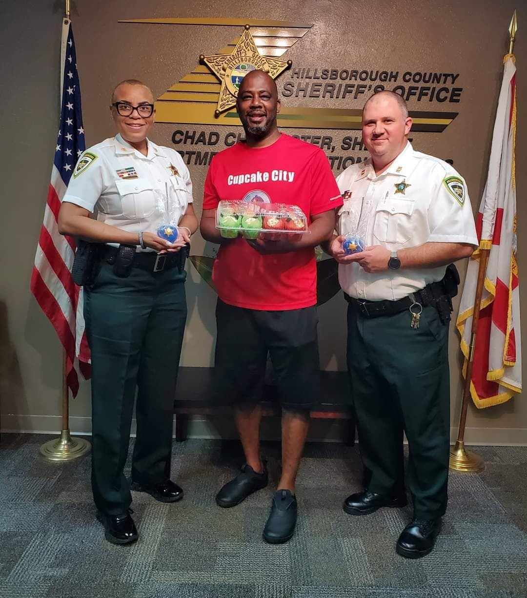 Chef Alvin delivering a tray of decorated cupcakes to two deputies at the Hillsborough County Sheriff's Office