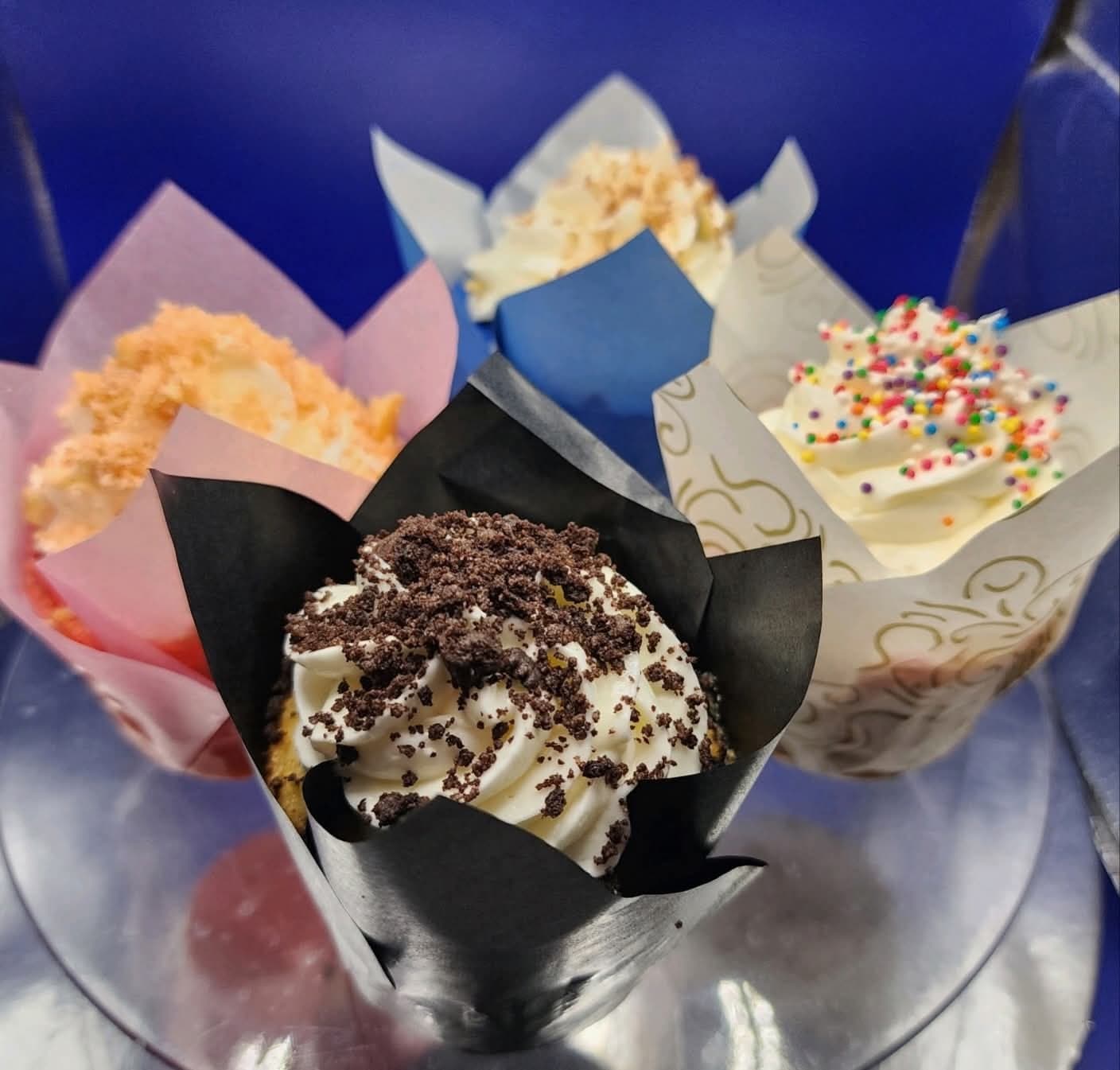 Close-up of four gourmet cupcakes from Cupcake City 813 topped with cookie crumbles and sprinkles