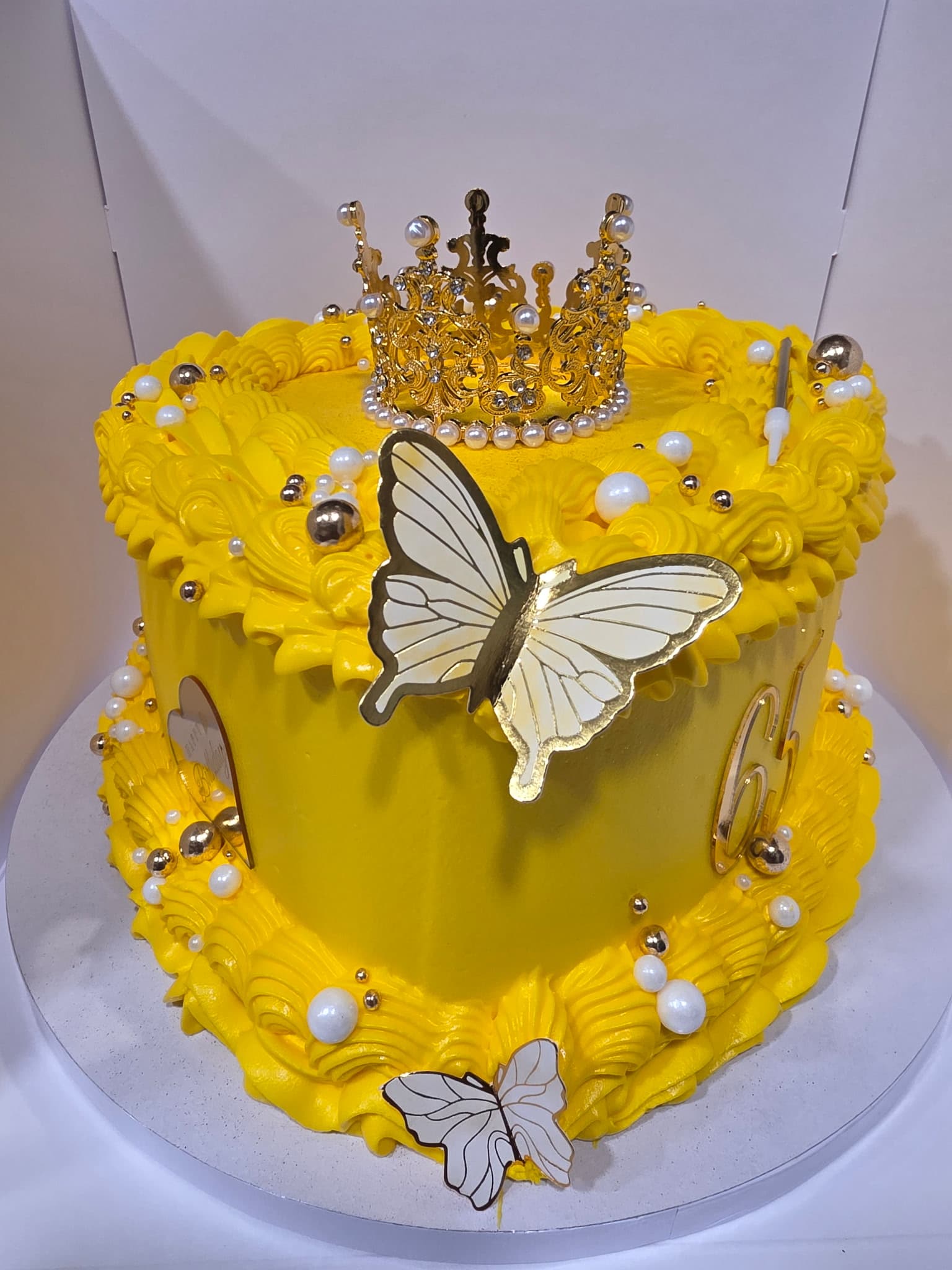 Yellow buttercream birthday cake with a gold crown, pearls, and butterfly details by Cupcake City 813